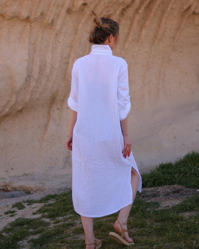 A back perspective of a white long shirt dress made of double gauze with a slit 