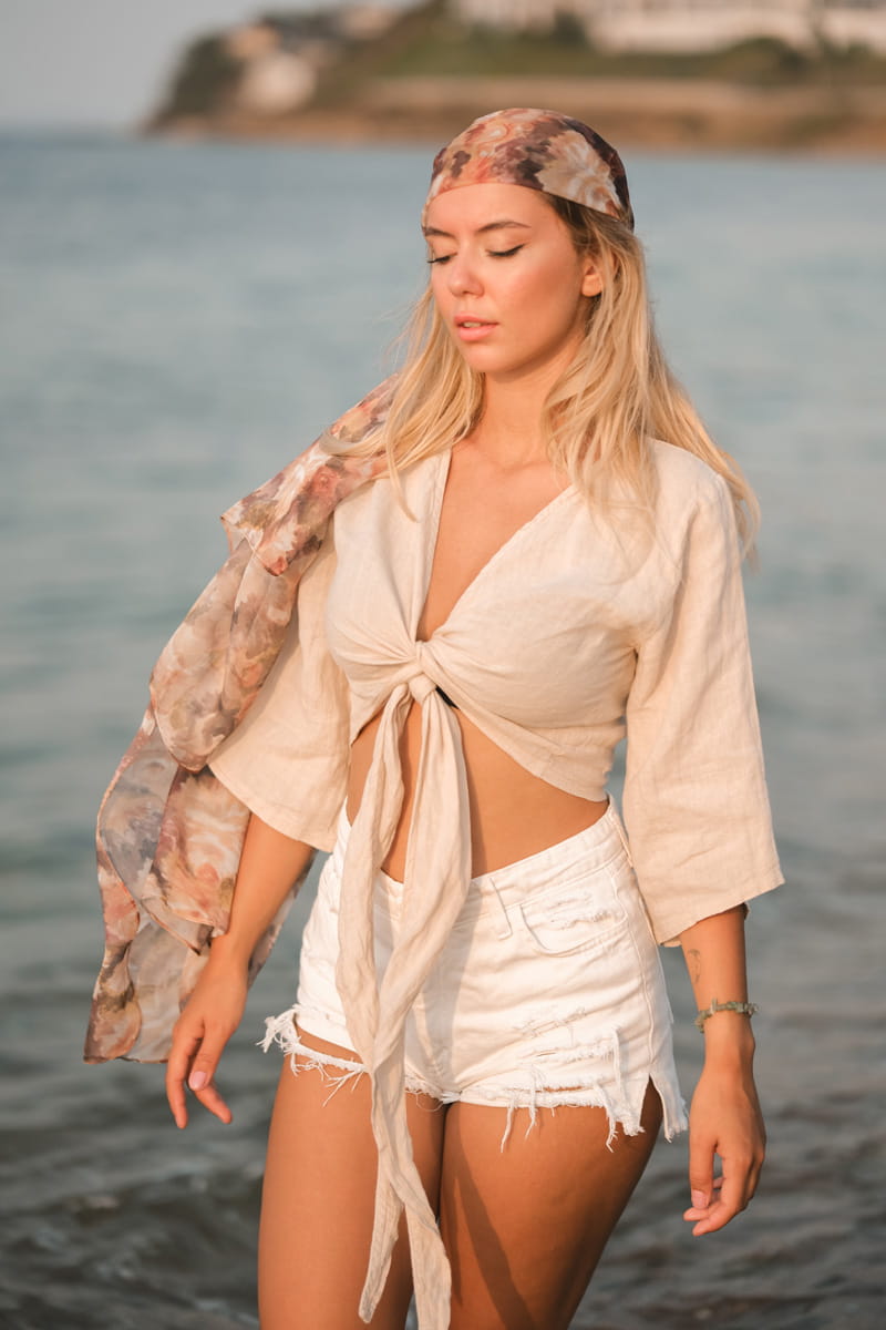 Woman in a beige short linen crop top standing by the water