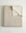 Beige gauze blanket with frayed edges on a light gray background