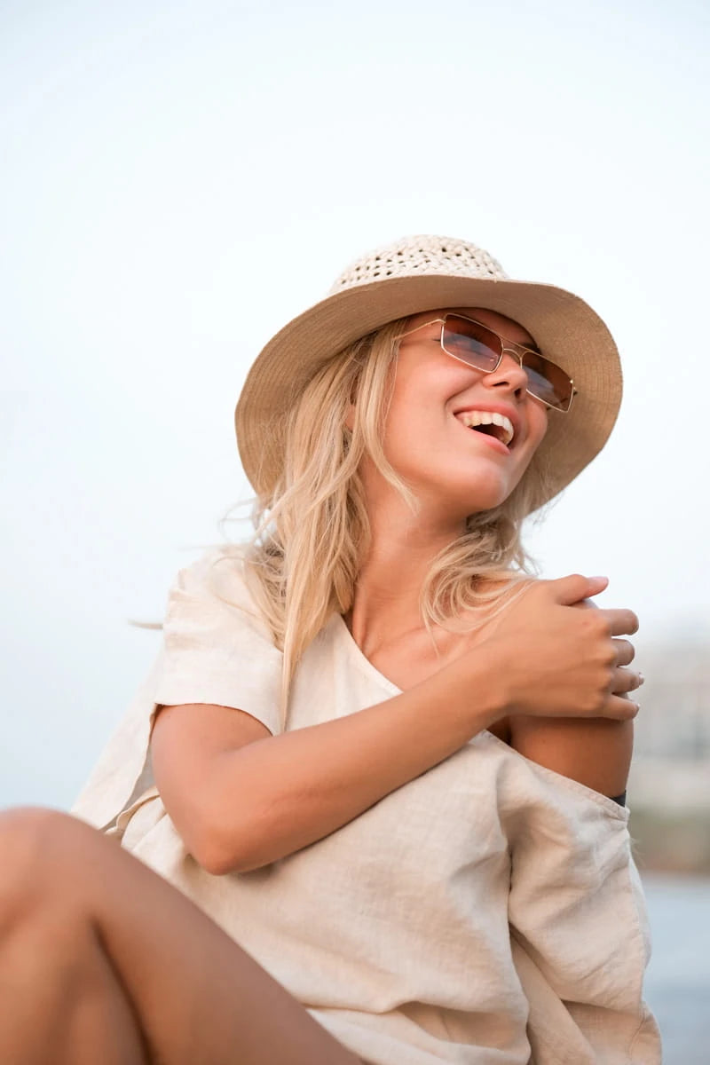 Woman wearing a round neck linen tshirt  and sunglasses on a beach