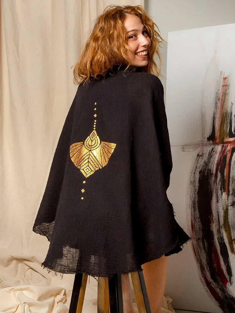 Woman wearing a black jacket with gold hand painted mocking bird design in a casual setting.