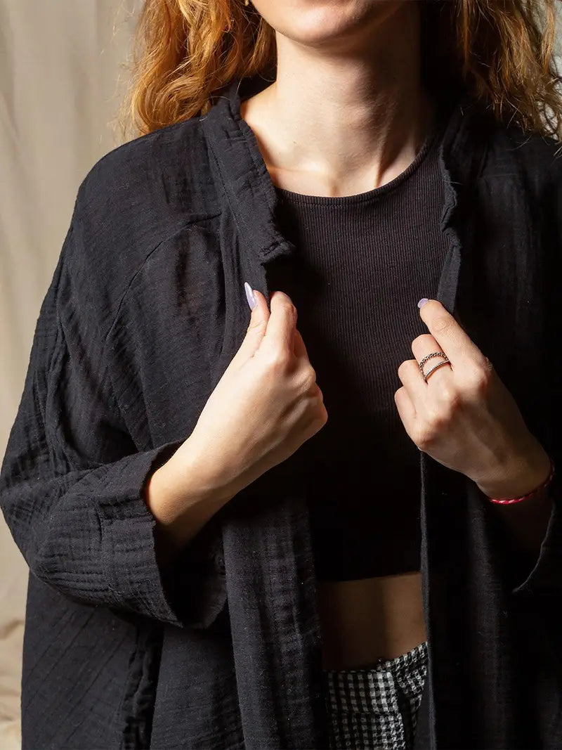 Person wearing a black double gauze muslin cotton kimono robe with a plain background