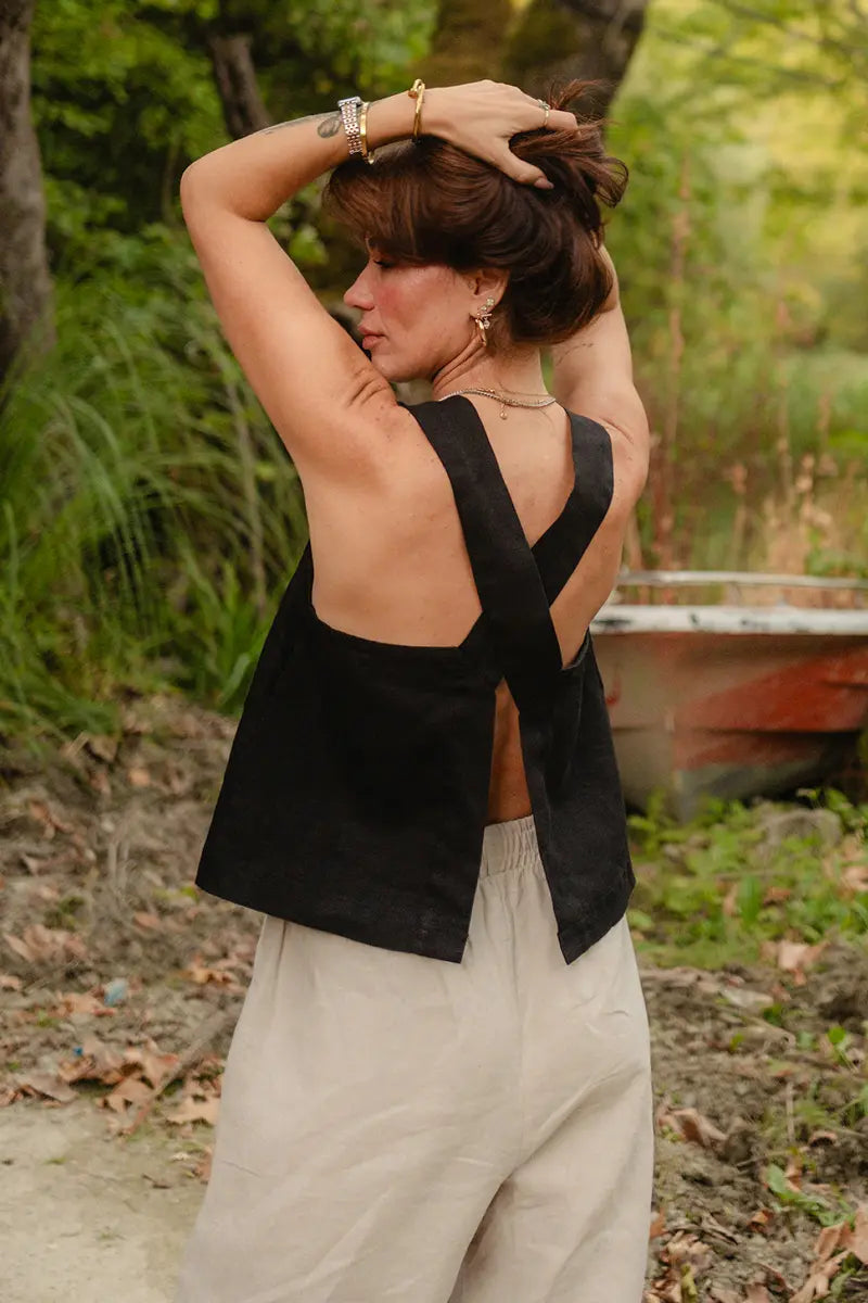 Woman wearing a black sleeveless cross back top with open back in a natural setting