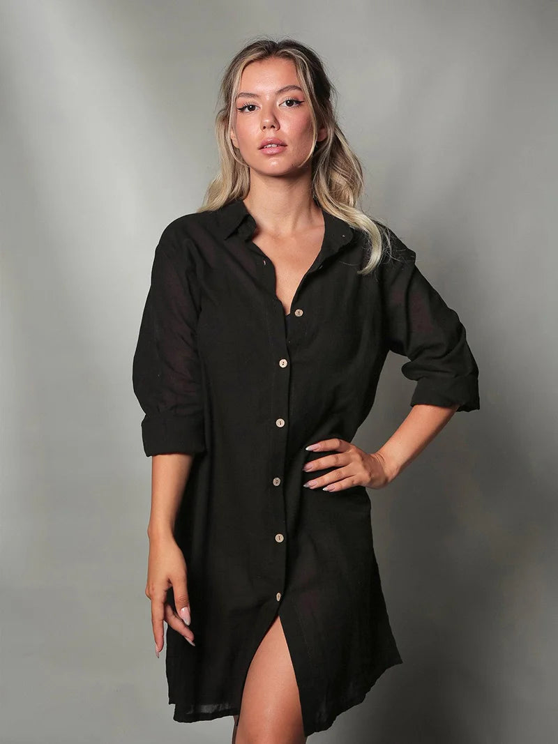 Woman wearing a black dress shirt with a slit on a gray background