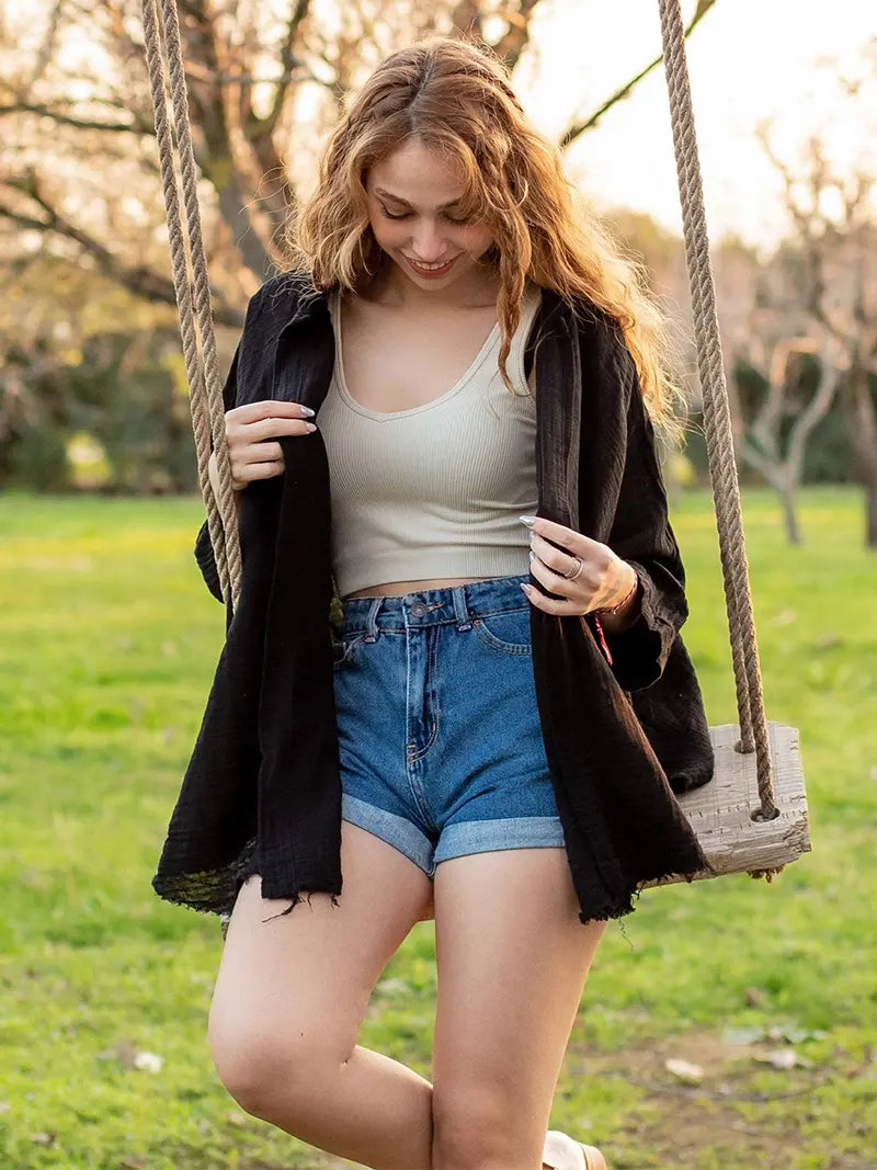 Woman with black muslin robe standing on a swing in a park