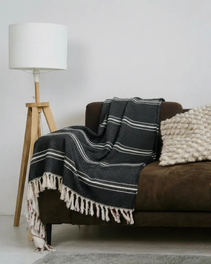Black and white striped blanket draped over a brown sofa in a living room setting.