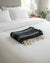 Black and white striped towel with tassels on a white bed