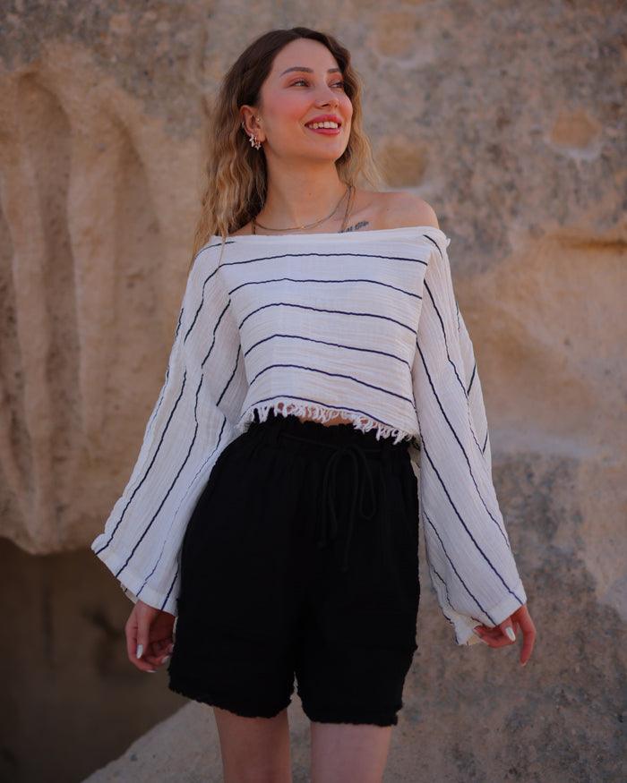 A close-up of black gauze shorts with a ruffled hemline, worn with a white cropped top.