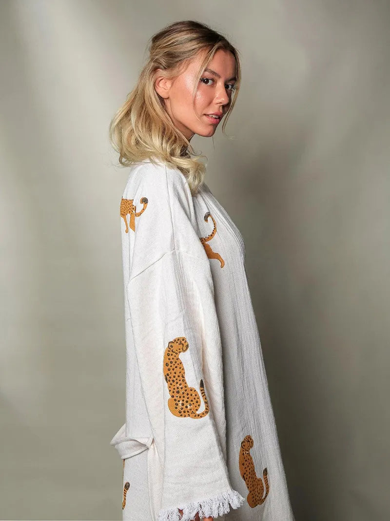 Woman wearing a white outfit with tiger print designs on a plain background