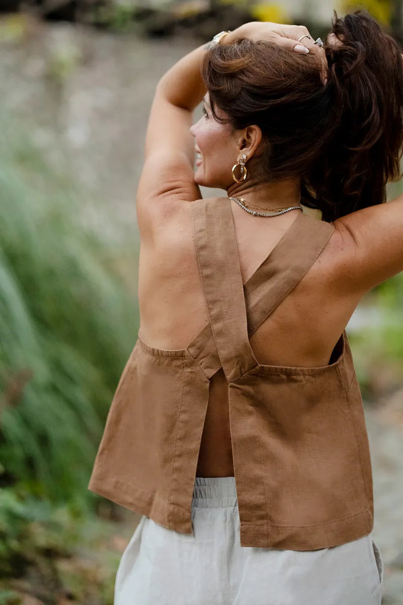 Woman wearing a brown sleeveless top with a blurred natural background
