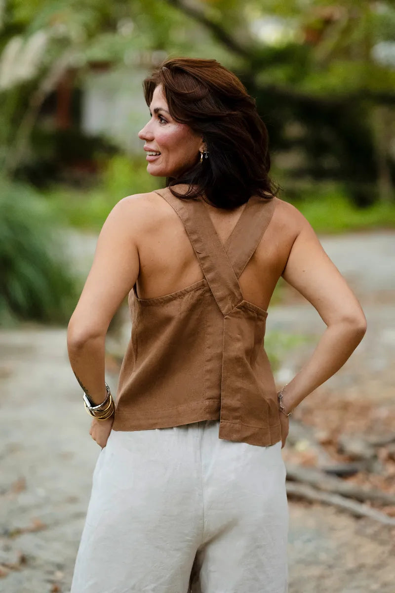 Woman wearing a brown sleeveless top with crossed straps outdoors