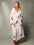 Woman in a white long leopard print robe against a grey background #Color_White / Orange