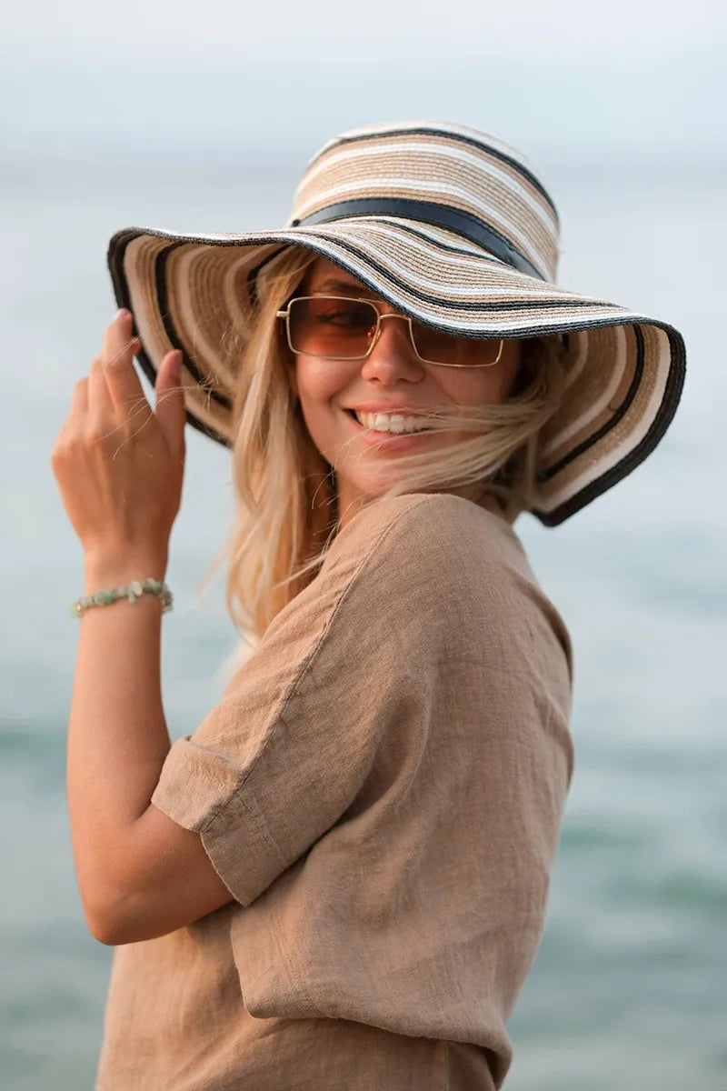 Woman wearing a linen tshirt and sunglasses by the ocean