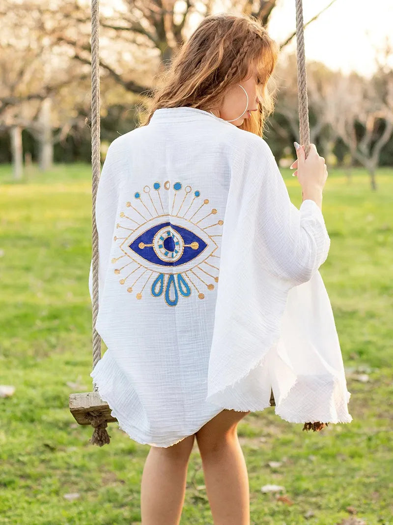 Person on a swing wearing a white double gauze cotton robe with a blue eye design