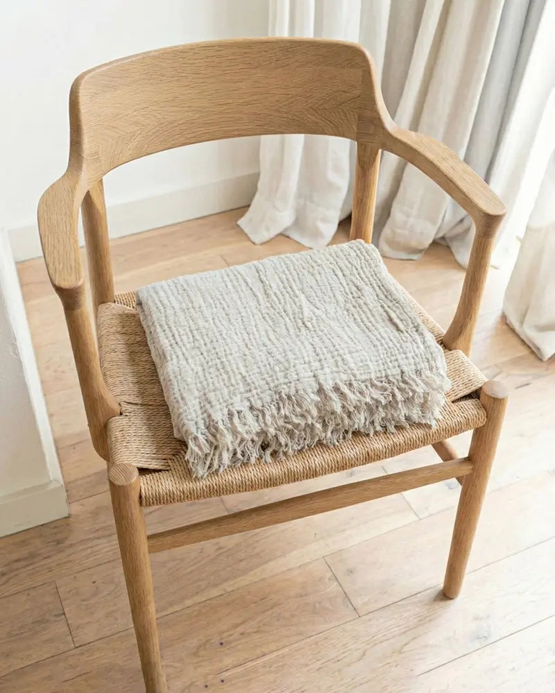 Wooden chair with a muslin blanket on a wooden floor