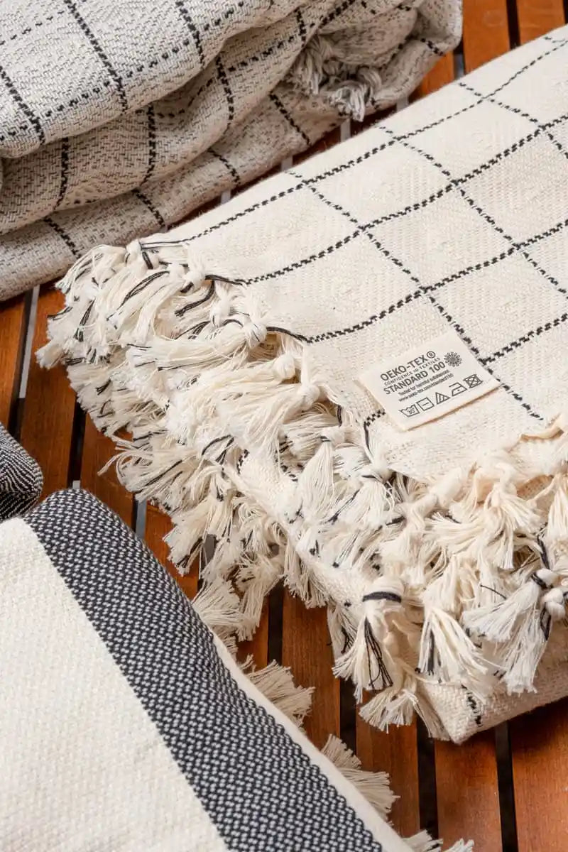 woven cotton blankets with tassels on a wooden surface