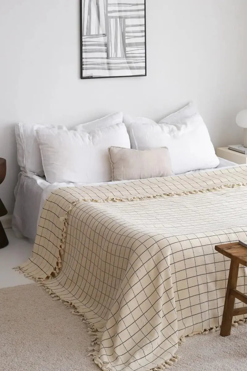 checkered bed blanket on a bed in a bedroom with abstract art on the wall.