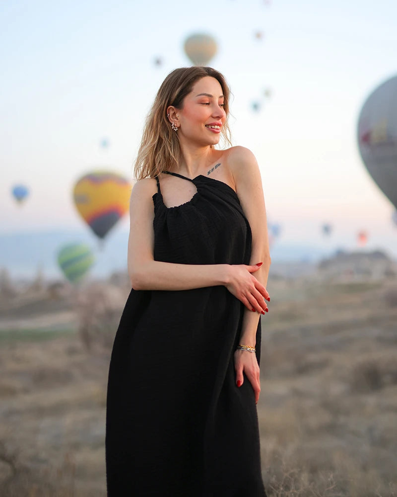 Woman in a muslin cotton black dress standing in front of hot air balloons