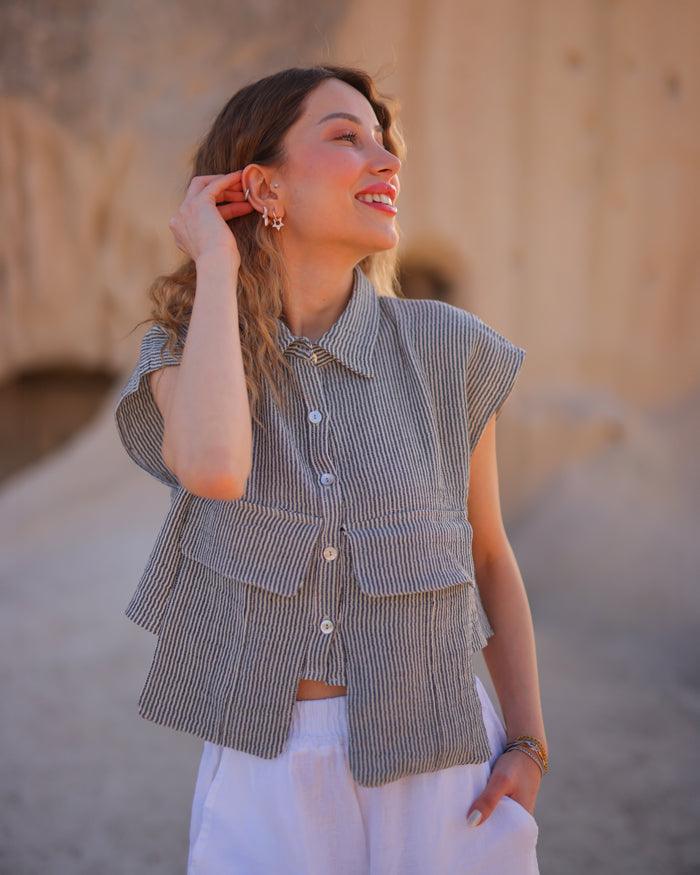 Close-up of sleeveless grey striped cropped shirt with collar and pocket detail