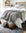 Bedroom with a bed covered in white bedding and a gray muslin throw blanket.