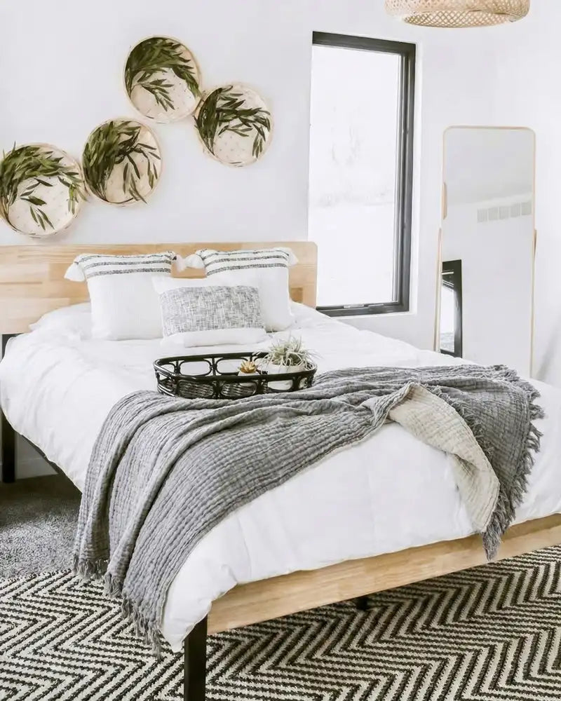 Neatly made bed with white bedding and gray muslin blanket in a bedroom setting.