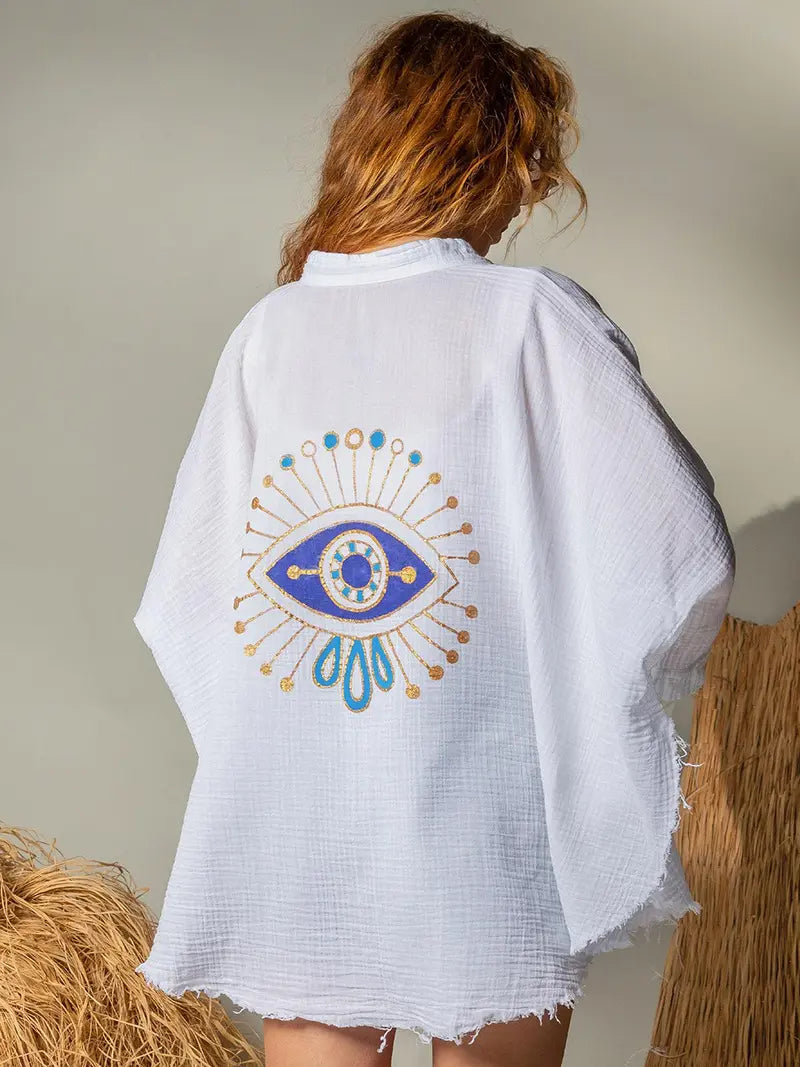 Person wearing a whitesoft double gauze muslin jacket with a blue eye design on a neutral background