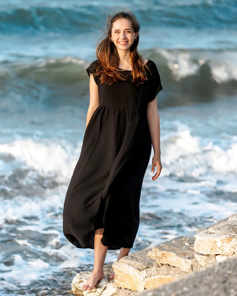 Woman in a Short Sleeve Black Midi dress standing on rocks by the ocean