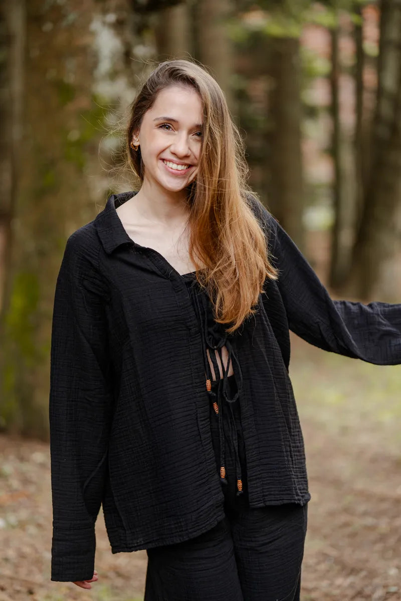Woman wearing a black muslin loungewear setwith a blurred forest background