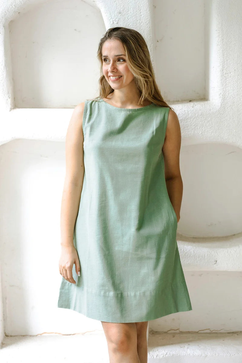 Woman wearing a light green shift dress against a white background