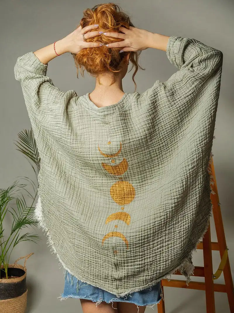 Person wearing a green textured robe with gold moon patterns, standing against a neutral background.