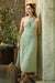 Light green halter neck midi dress by a textured wall with a suitcase — soft muslin cotton drape