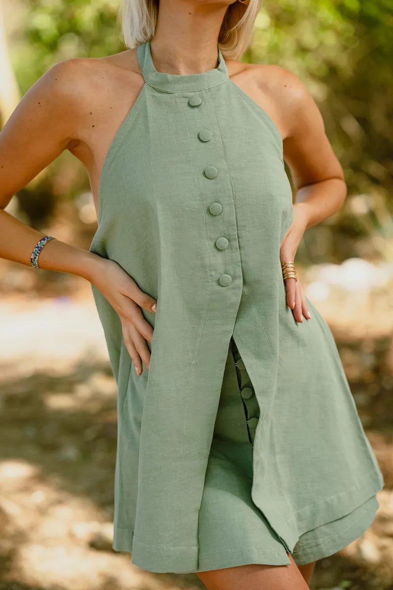 Woman wearing a green halter neck dress with buttons in an outdoor setting
