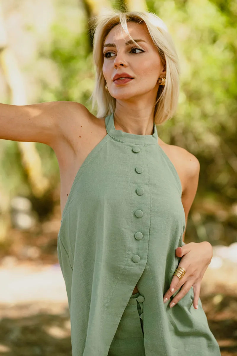 Woman wearing a green halter neck dress with buttons in a natural setting