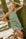 Woman in a green linen halter neck dress leaning against a tree