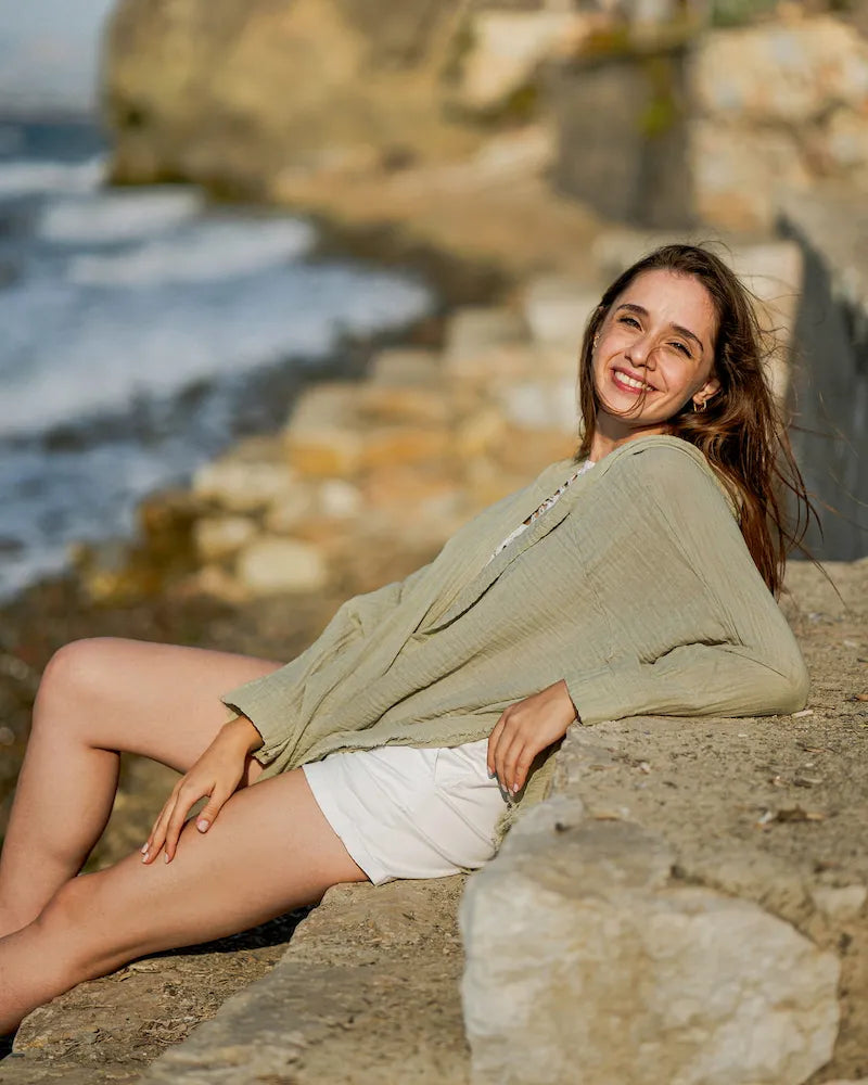 woman in green hooded cardigan laying on beach 