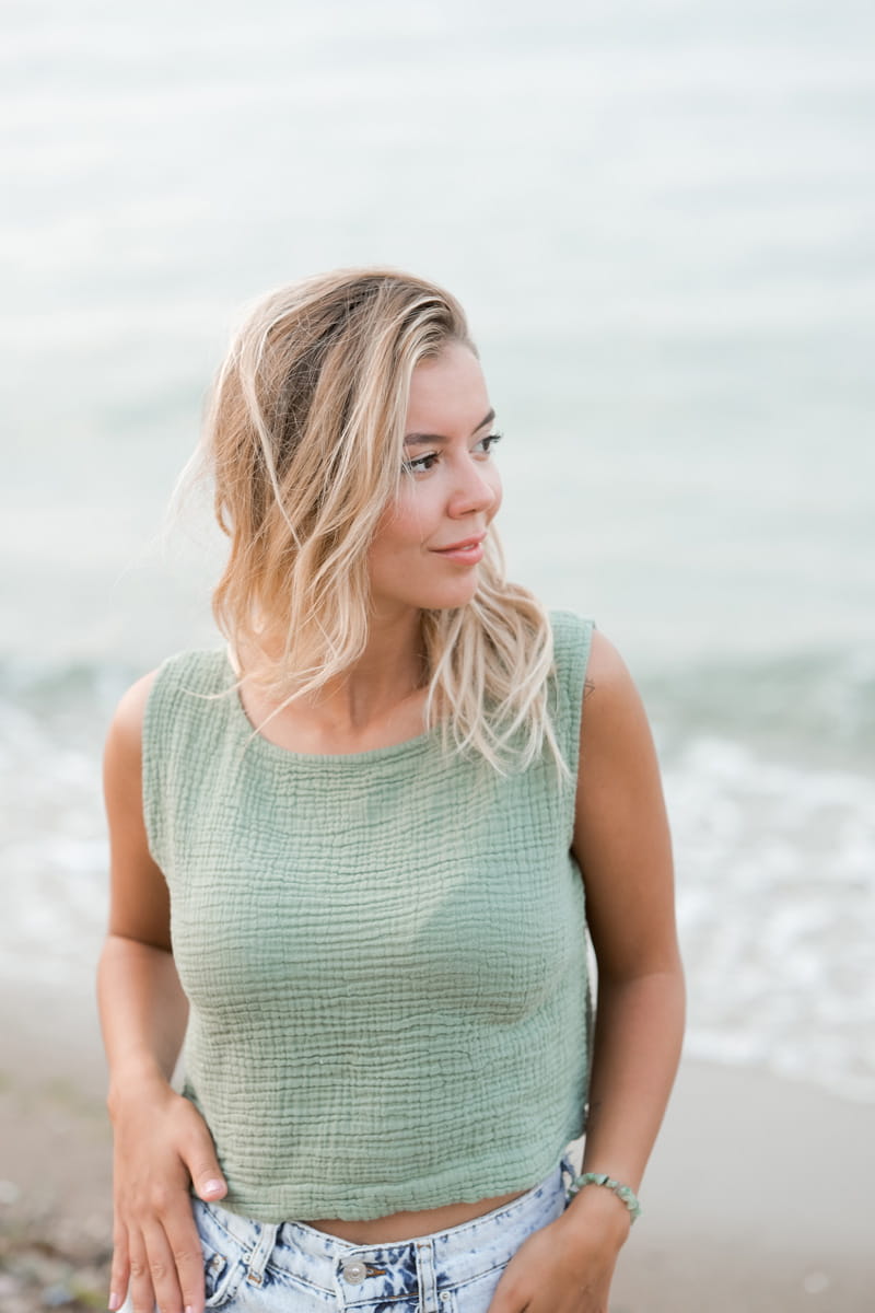 Woman wearing a green sleeveless top with a blurred natural background
