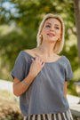Woman wearing a grey top with a blurred green outdoor background