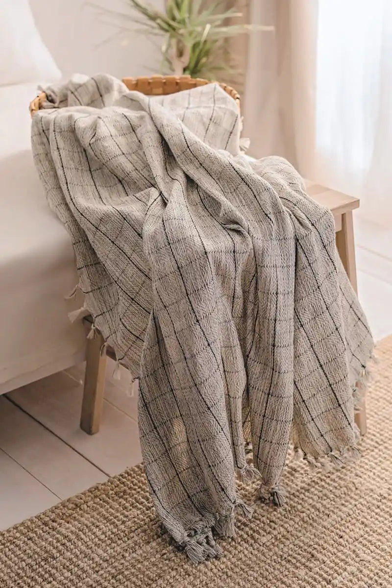 Plaid blanket draped over a wooden stool in a home setting