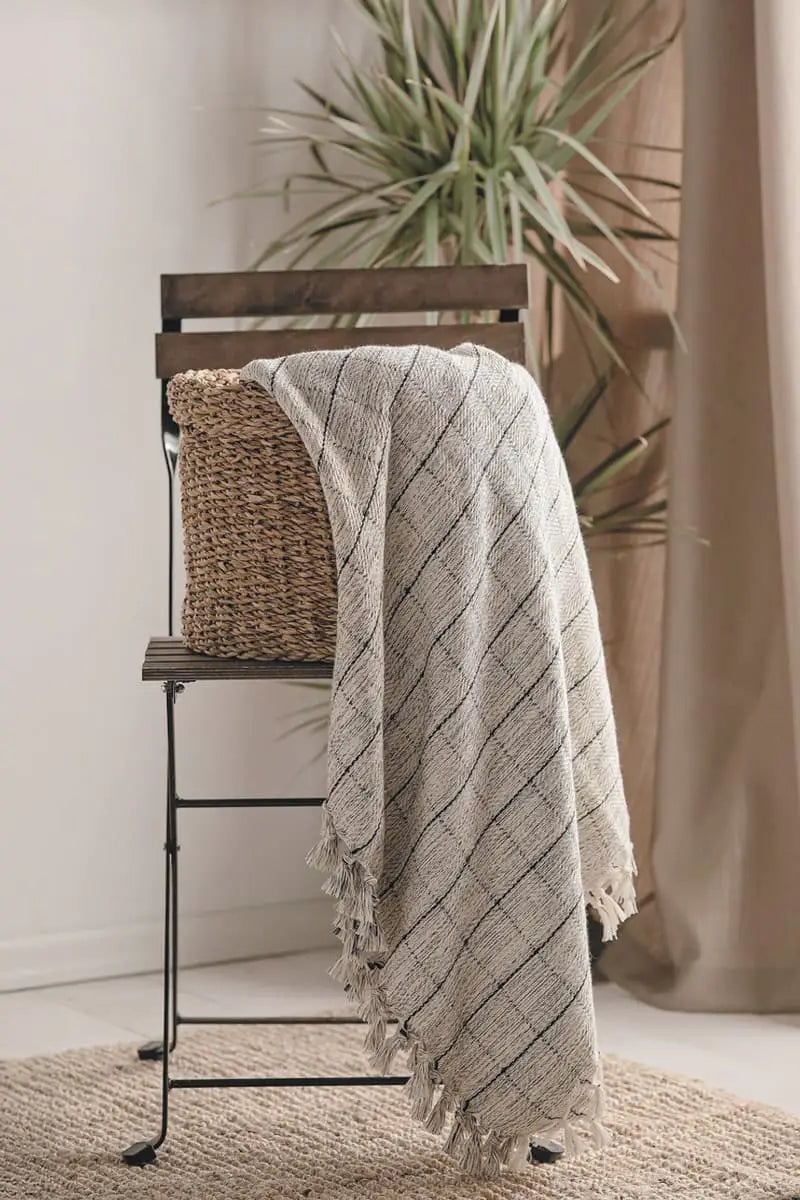 grey window pane blanket draped over a wooden chair with a plant in the background