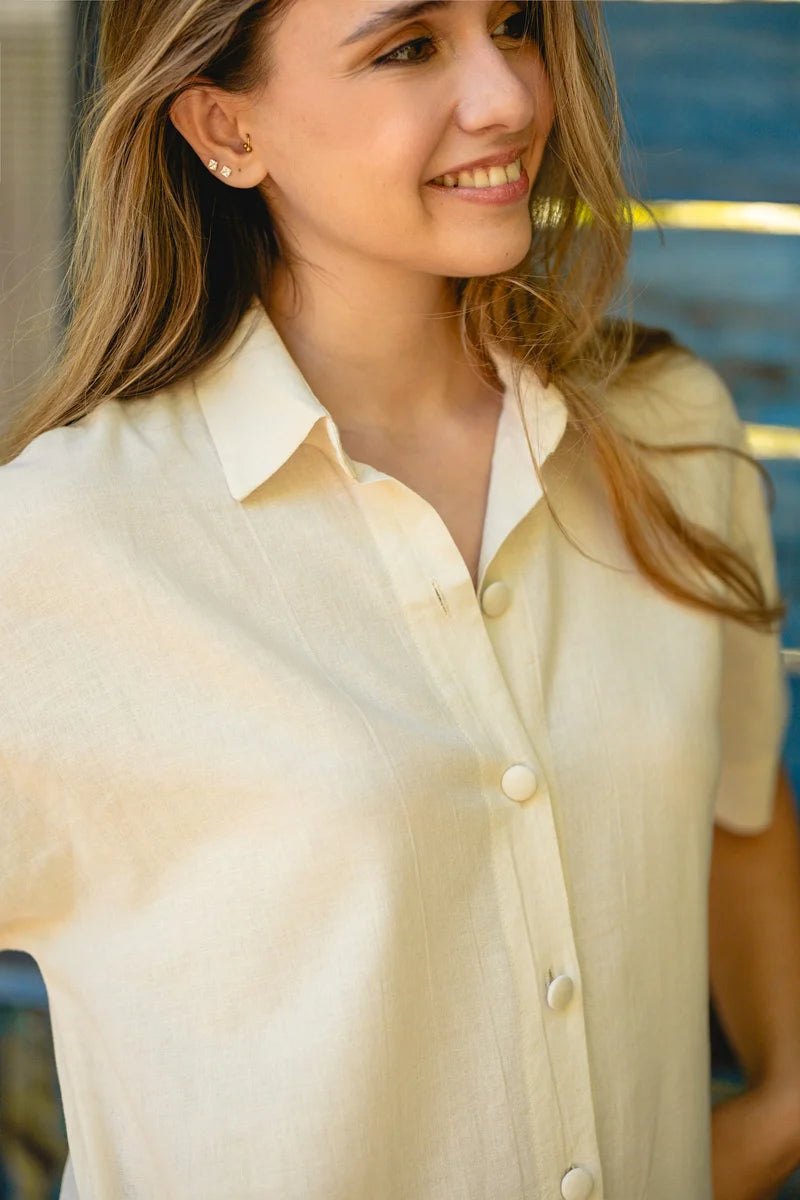 Woman wearing a light-colored shirt dress with a blurred background