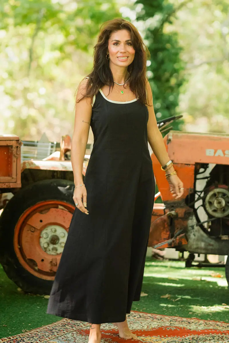 Woman in a black dress standing in front of a vintage tractor with greenery in the background