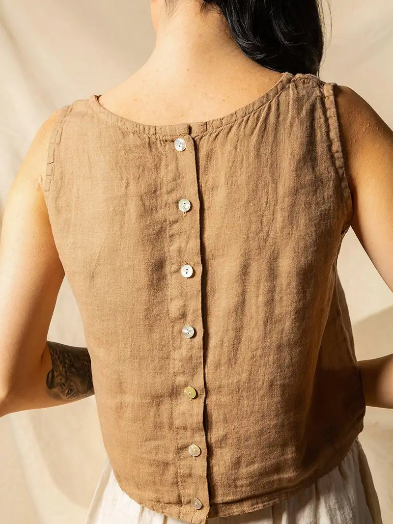 Brown sleeveless top with buttons down worn by a person against a neutral background