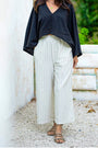 Woman in a black top and pinstripe wide leg linen pants outdoors — soft linen-cotton blend, pleated cut