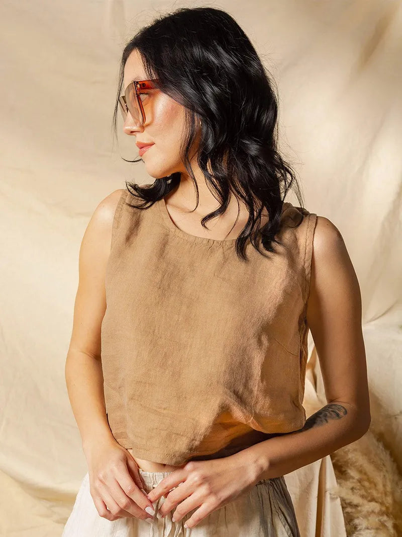 Woman wearing a brown round neck sleeveless top against a beige background