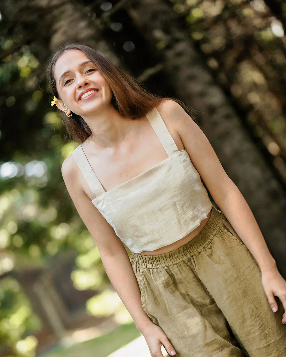 Woman wearing a linen crop top and green linen pants standing outdoors with trees in the background