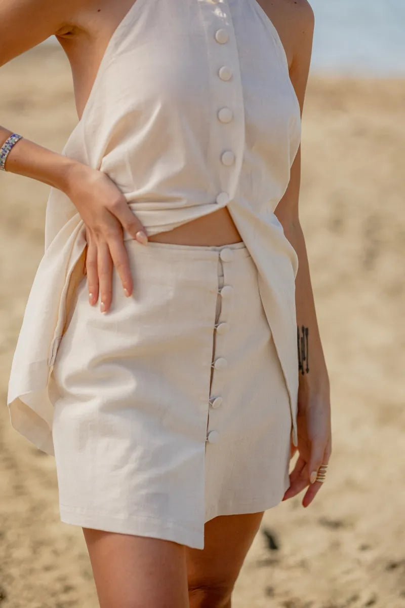 Person wearing a beige button-up top and short set in a desert setting
