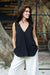 Woman in a black v-neck linen shell top and white pants outdoors — soft linen-cotton blend