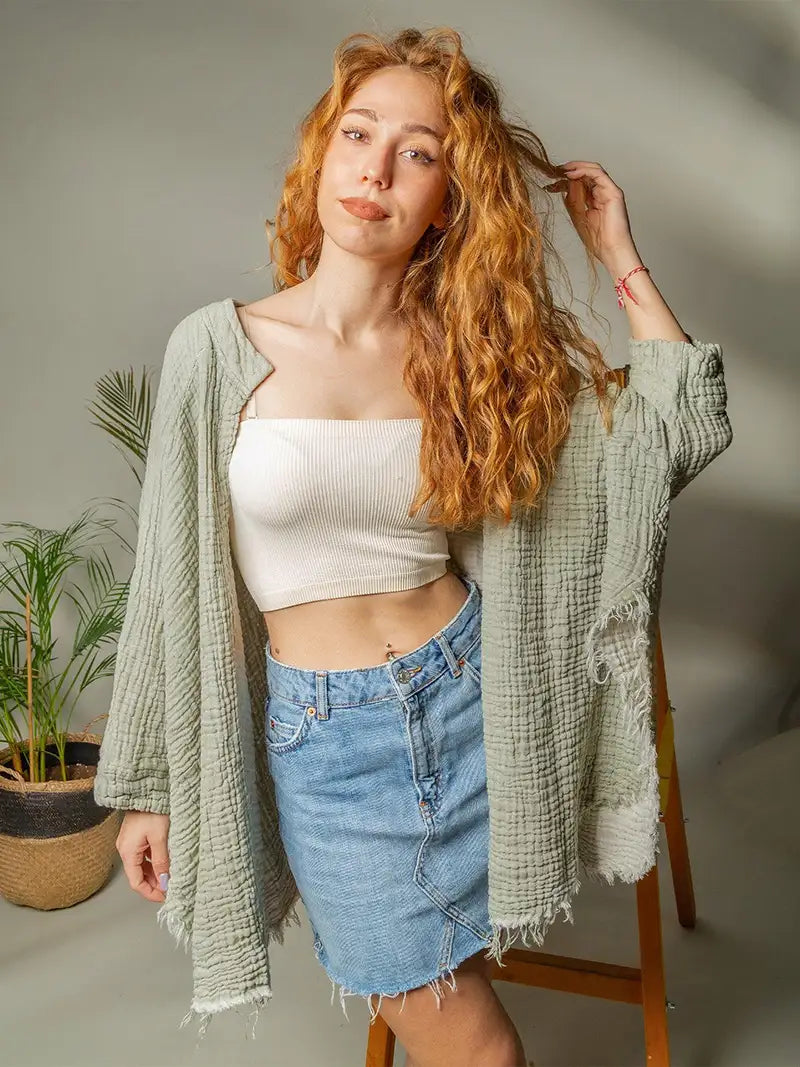 Woman with red hair wearing a white top and denim skirt, standing indoors.