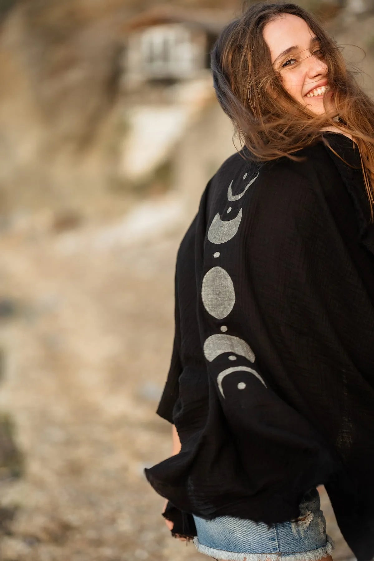Woman wearing a black robe with silver moon phase design outdoors