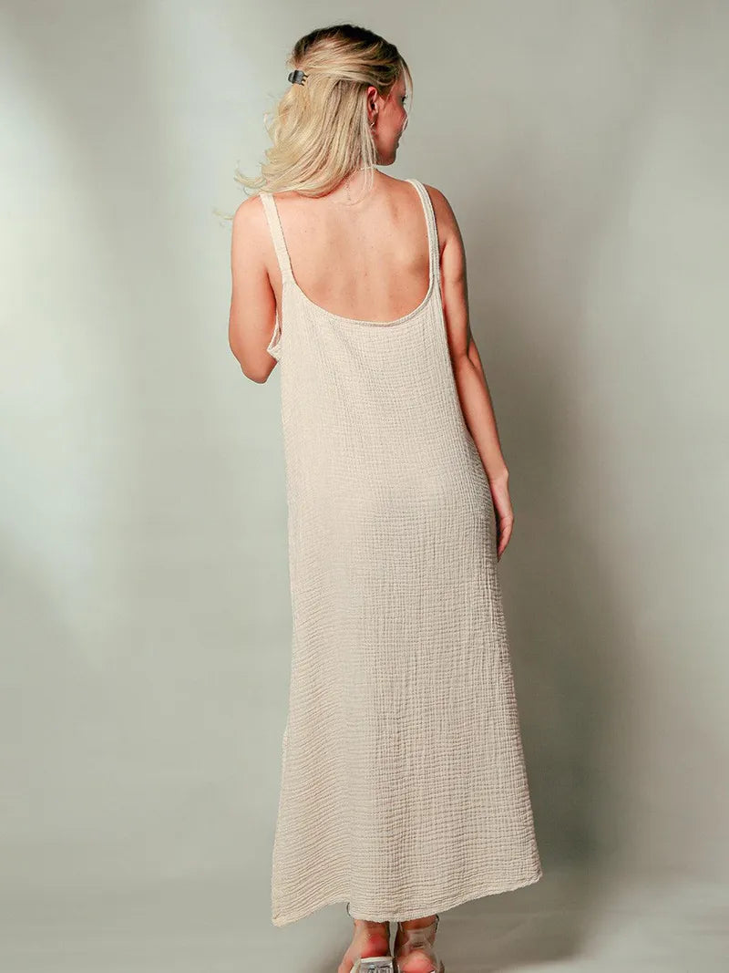 Woman wearing a beige sleeveless dress against a plain background